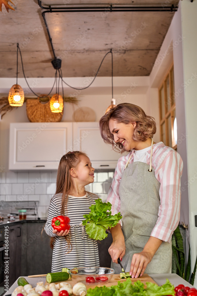 beautiful adult mother and daughter are going to prepare fresh salad together, having vegetables. food, family concept - obrazy, fototapety, plakaty 
