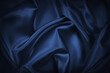 Abstract blue black background. Navy blue silk satin texture background. Beautiful soft wavy folds on shiny fabric. Dark elegant background for your design.