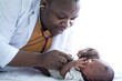© chomplearn_2001 - African doctor listening to heart beat  of newborn baby with stethoscope, newborn baby 15 days old lying on bed