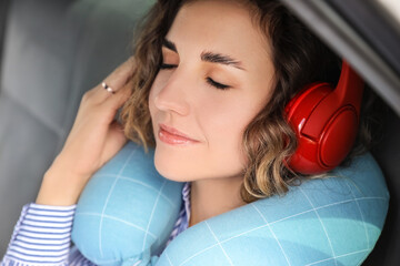 Canvas Print - Beautiful young woman with travel pillow and headphones sleeping in car