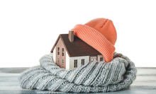 Figure Of House And Warm Clothes On Table Against White Background. Concept Of Heating Season