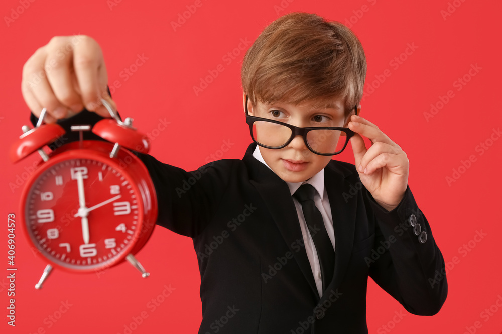 Little businessman with alarm clock on color background