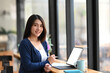 © Prathankarnpap - Attractive young woman designer sitting at her workstation and smiling to camera.