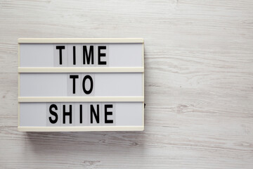'time to shine' on a lightbox on a white wooden surface, top view. flat lay, overhead, from above. s