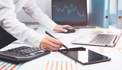 Wall Mural - Stock exchange trade and forex financial concept. Laptop with graphs on desk with copy space. Hand with calculator. Distant learning or broker working from home or office, online business.