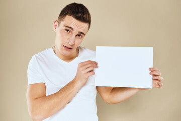 man in white t-shirt sheet of paper in hands Copy Space cropped view beige background