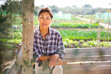 Portrait of happy smiling asian woman in her vegetable garden on sunny fall day