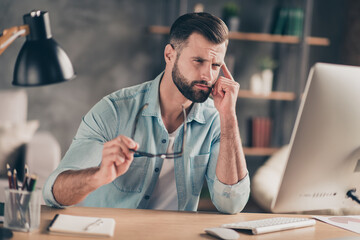 Sticker - Photo portrait of tired man touching temple with finger having headache at table in modern industrial office indoors