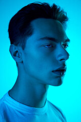 Wall Mural - Style. Handsome caucasian man's portrait isolated on blue studio background in neon, monochrome. Beautiful male model. Concept of human emotions, facial expression, sales, ad, fashion and beauty.