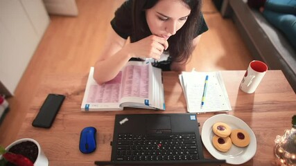 Poster - A female student uses a laptop while sitting at the table. The thought process in distance education using high-speed Internet. There is water on the table and cookies on the plate.
