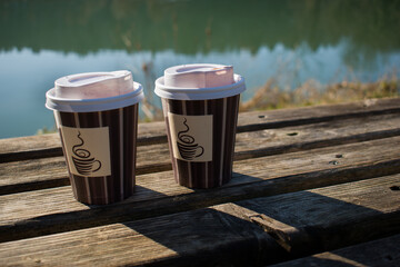 Two cups of coffee to go on the bench in the nature