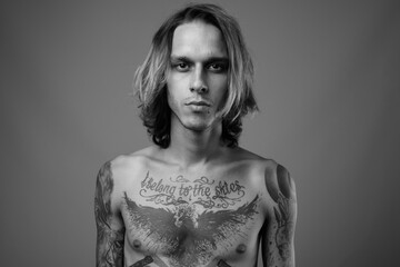 Studio shot of rebellious young man shirtless against gray background