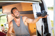 © photoschmidt - Smiling man in a camper van pointing a camera at himself