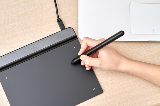 Girl draws on a graphics tablet with pen. Close-up, selective focus