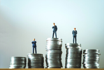 Miniature people businessman on top of stacks coins in money communication on white background