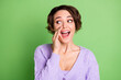 Photo of positive person arm near open mouth tell look empty space wear violet isolated on green color background