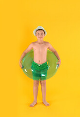 Canvas Print - Cute little child in beachwear with bright inflatable ring on yellow background