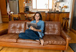 © SB Arts Media - Woman enjoying life at home sitting on sofa using digital tablet. In Coronavirus and New Normal