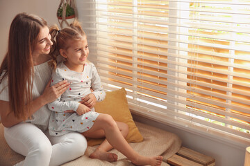 happy mother with little daughter near window at home