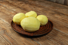 Raw Peeled Potatoes Lie In A Ceramic Plate.The Plate Is On A Wooden Table.