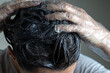 © vejaa - Closeup woman hands dyeing hair. Middle age woman colouring dark hair with gray roots at home