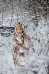 Poster - Beautiful blond toddler child, boy with white knitted handmade overall, holding lantern in the snow