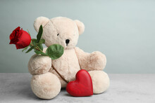Cute Teddy Bear With Heart And Red Rose On Light Grey Stone Table. Valentine's Day Celebration