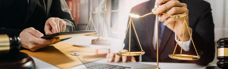 Justice and law concept.Male judge in a courtroom with the gavel, working with, computer and docking keyboard, eyeglasses, on table in morning light