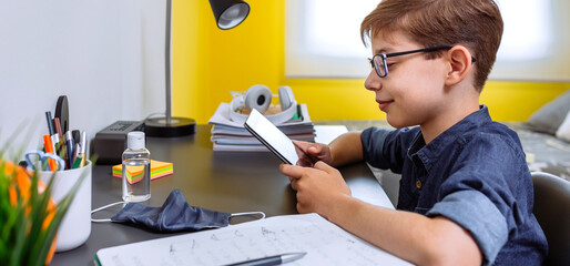 Wall Mural - Teenager doing homework with a tablet in his room