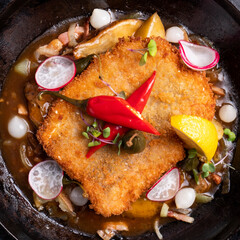 Wall Mural - Fried schnitzel in a pan. Top view, closeup