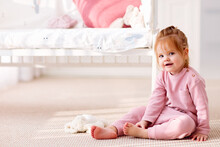 Cute Toddler Baby Girl Sitting On The Carpet In The Nursery Room