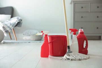 Poster - Bucket, mop and different cleaning products on floor indoors. Space for text