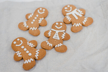 Smiling gingerbread man with sugar, spices, and vintage rolling pin on rustic, textile linen background.