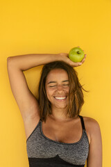 Healthy, smiling woman holding an apple on a yellow background. Health, diet, eating, slimming