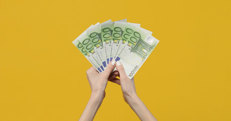 Female hands holding euro banknotes on a yellow background. Euro Money in woman hand. Euro cash background