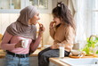 Muslim Mom In Hijab And Her Little Daughter Eating Snacks In Kitchen