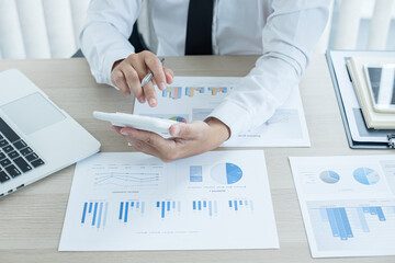 The businessman hand sits at their desks and calculates financial graphs showing the results of their investments planning the process of successful business growth