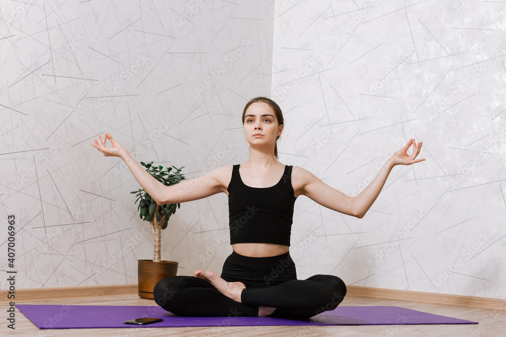 Tranquil woman in activewear sitting on mat in Lotus pose with crossed ...