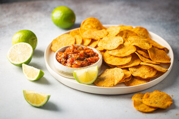 Wall Mural - Single big white plate of yellow corn tortilla nachos chips with salsa sauce over white table