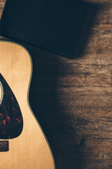 Wall Mural - A guitar and a bible on a wooden background in a dimly lit environment. Soft light and worship