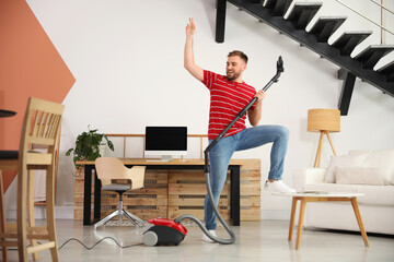 Canvas Print - Young man having fun while vacuuming at home