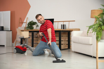 Canvas Print - Young man having fun while vacuuming at home