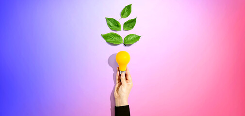 Poster - Person holding a light bulbs with green leaves