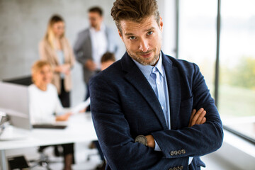 Wall Mural - Handsome young business man standing confident in the office