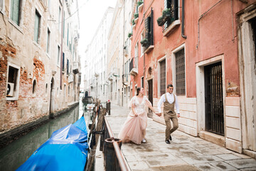 Wall Mural - Wedding couple holding hands, groom and bride together on wedding day in Venice, Italy