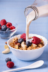 Sticker - on lavender blue table, breakfast food with fresh milk, in bowl mix of dried fruits, whole grains, candied ginger, blueberries and raspberries