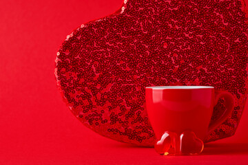 Red cup mug and two chocolate hearts and big box behind it on scarlet or red background. Flat lay composition. Valentines Day concept. Top view, copy space.