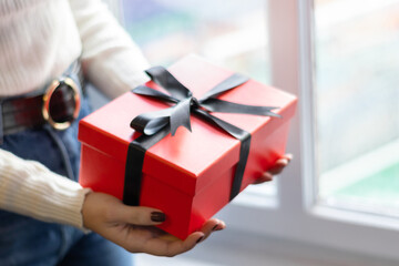 A woman holding a red gift box between her hands. Happy valentine’s day, red color, heart icon, isolated background