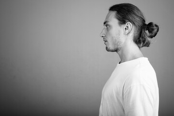 Young handsome man wearing white shirt against gray background