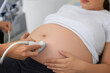 Doctor screening tummy of pregnant woman with ultrasound
